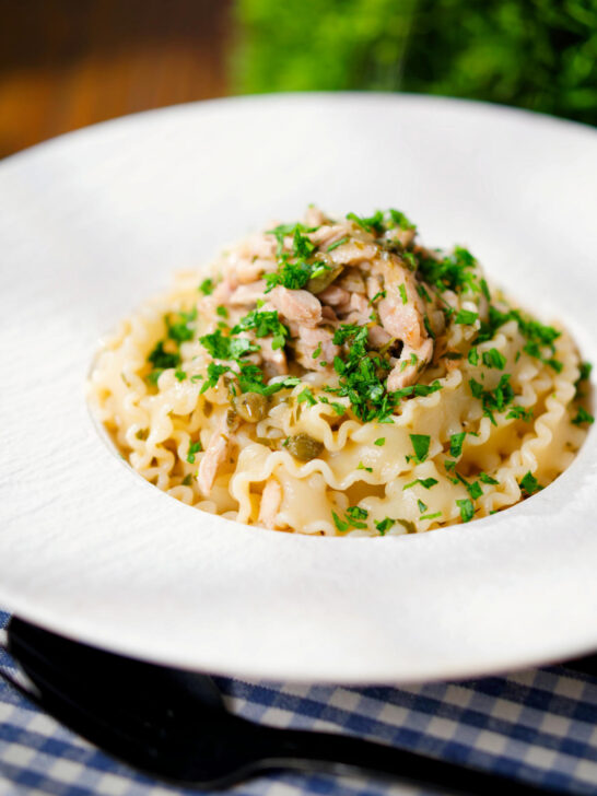 Lemon and caper chicken piccata pasta (malfadine) garnished with fresh parsley.