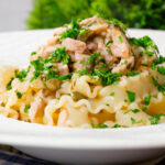 Close-up lemon and caper chicken piccata pasta (malfadine) garnished with fresh parsley.