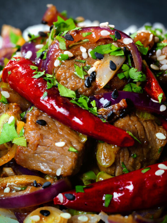 Close-up Chinese Xinjiang lamb stir fry with cumin, dried chillies and red onion.