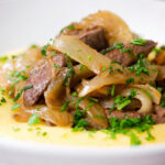 Close-up Fegato alla Veneziana (Italian fried liver and onions) served with polenta.