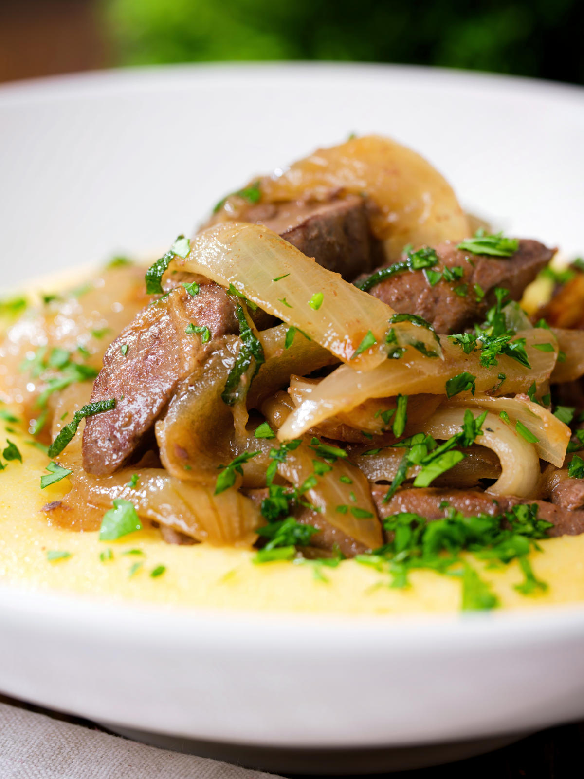 Close-up Fegato alla Veneziana (Italian fried liver and onions) served with polenta.