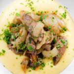 Overhead close-up Fegato alla Veneziana (Italian fried liver and onions) served with polenta.