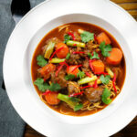 Overhead M&igrave; B&ograve; Kho, Vietnamese beef and egg noodle stew with carrots and spring onions.