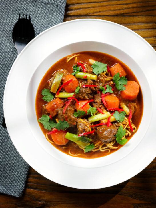 Overhead M&igrave; B&ograve; Kho, Vietnamese beef and egg noodle stew with carrots and spring onions.