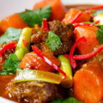 Close-up M&igrave; B&ograve; Kho, Vietnamese beef and egg noodle stew with carrots and spring onions.