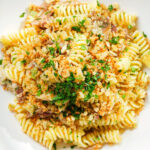Close-up overhead smoked mackerel pasta (fusilli) with chilli and a lemon crumb.
