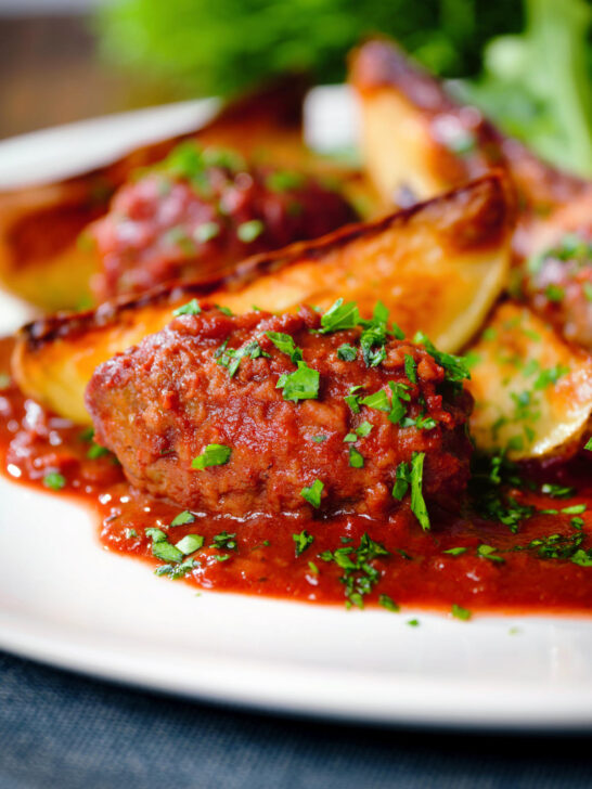 Soutzoukakia (Greek beef meatballs) in tomato sauce with potato wedges.