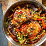 Overhead sweet and sour pork chops with peppers, red onion and pineapple, served in a pan.