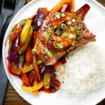 Overhead sweet and sour pork chops with peppers, red onion and pineapple, served with rice.