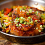 Sweet and sour pork chops with peppers, red onion and pineapple, served in a pan.