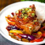Sweet and sour pork chops with peppers, red onion and pineapple, served with rice and spring onions.
