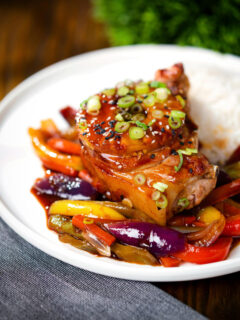 Sweet and sour pork chops with peppers, red onion and pineapple, served with rice and spring onions.