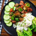 Overhead Vietnamese shaking beef (bò lúc lắc) served with cucumber, jasmine rice and lettuce.