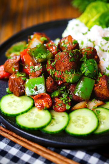 Vietnamese shaking beef (bò lúc lắc) served with cucumber, jasmine rice and lettuce.