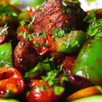 Close-up Vietnamese shaking beef (bò lúc lắc) served with cucumber, jasmine rice and lettuce.