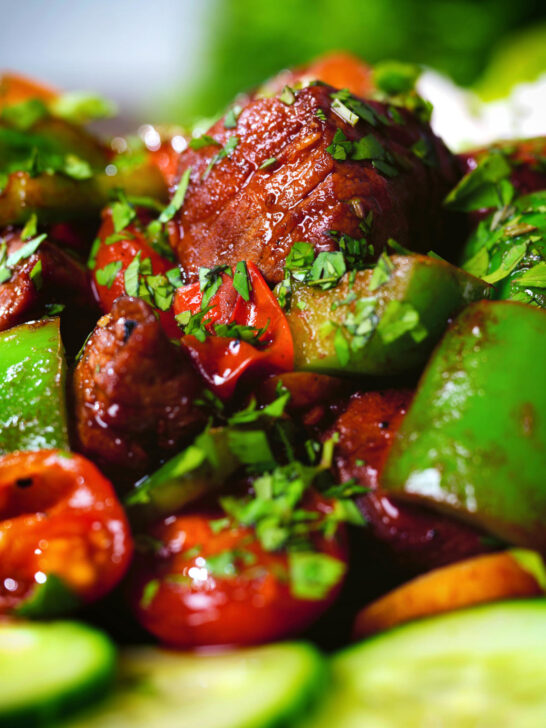 Close-up Vietnamese shaking beef (bò lúc lắc) served with cucumber, jasmine rice and lettuce.