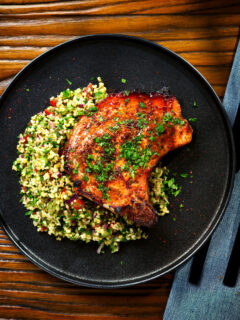 Overhead baked harissa and honey glazed pork chops served with parsley and tabbouleh.