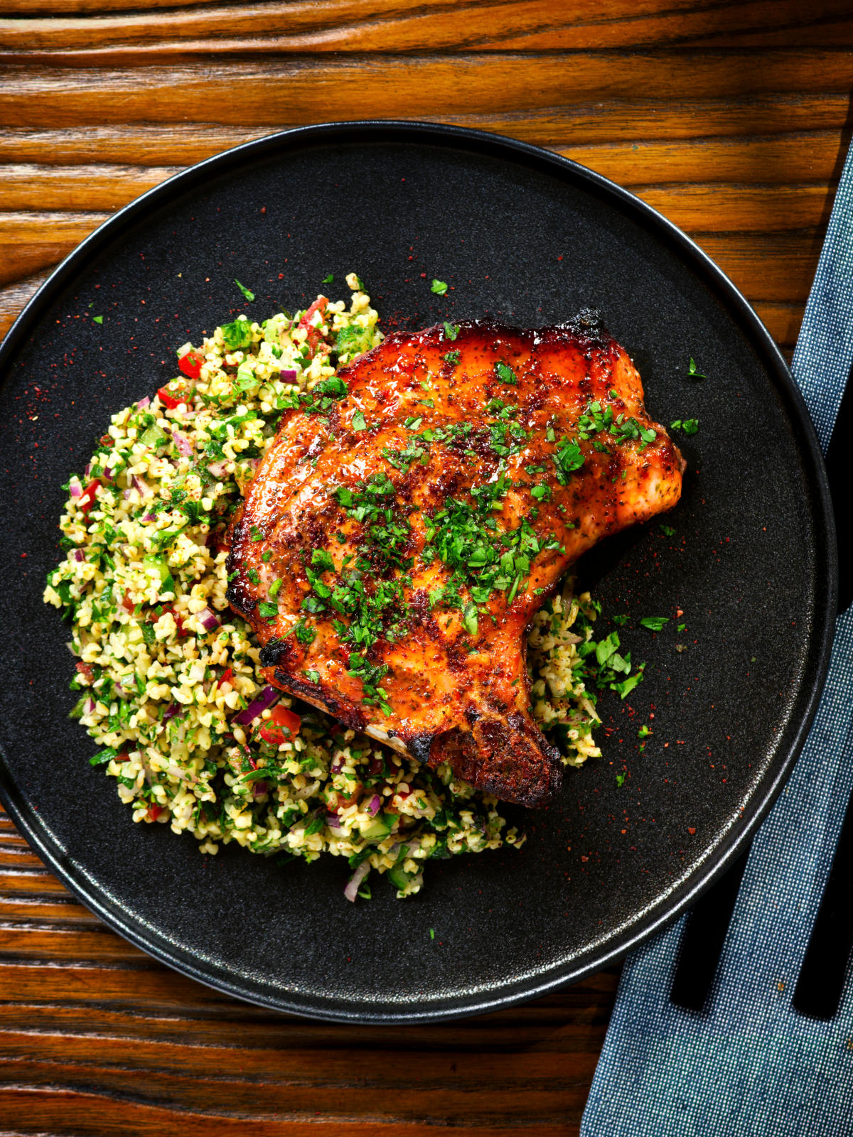 Overhead baked harissa and honey glazed pork chops served with parsley and tabbouleh.