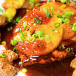 Close-up baked Hawaiian chicken breast with pineapple huli huli sauce and crushed new potatoes.