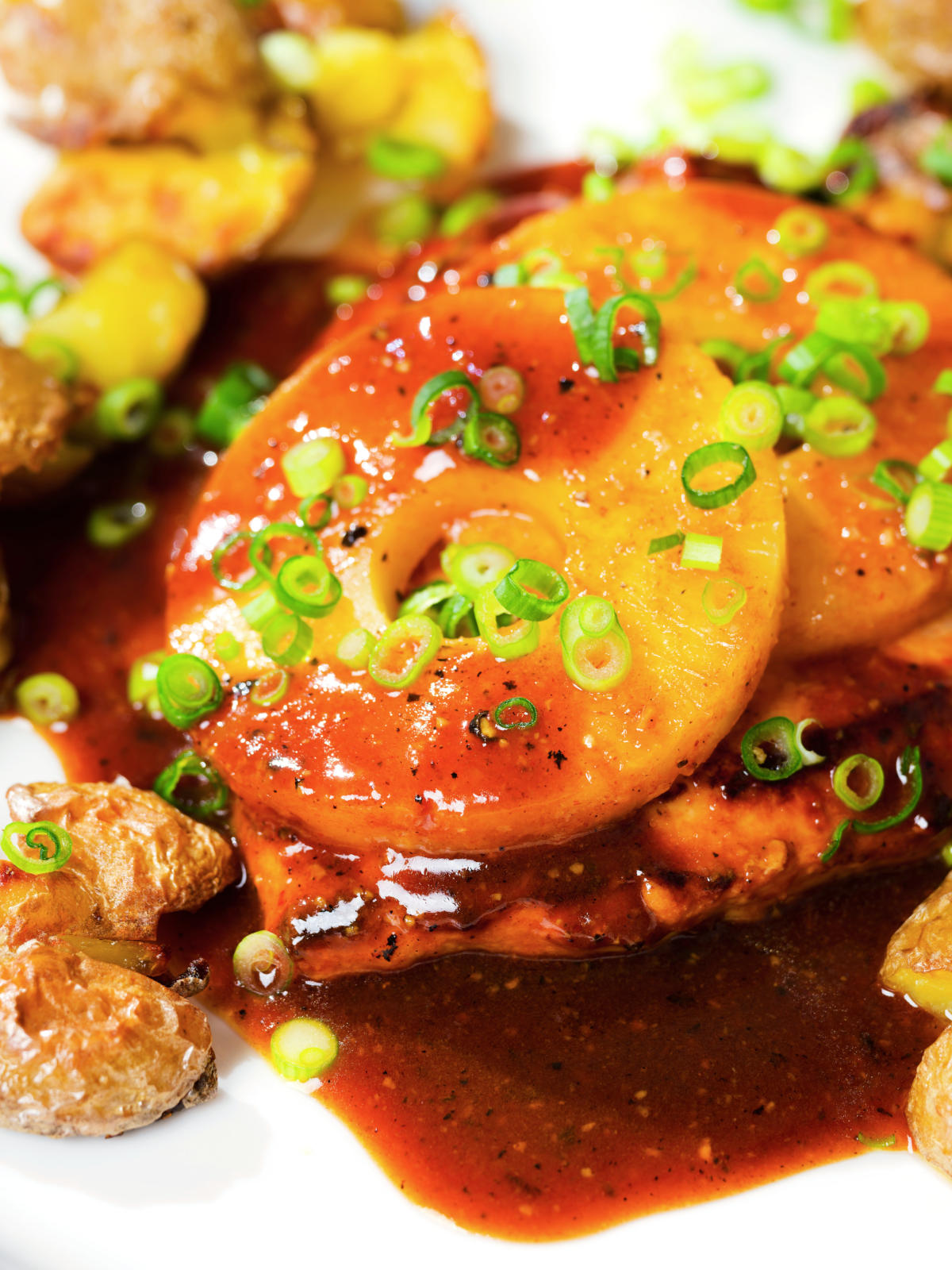 Close-up baked Hawaiian chicken breast with pineapple huli huli sauce and crushed new potatoes.