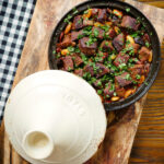 Overhead harissa beef tagine with prunes and almonds in a traditional style pot.