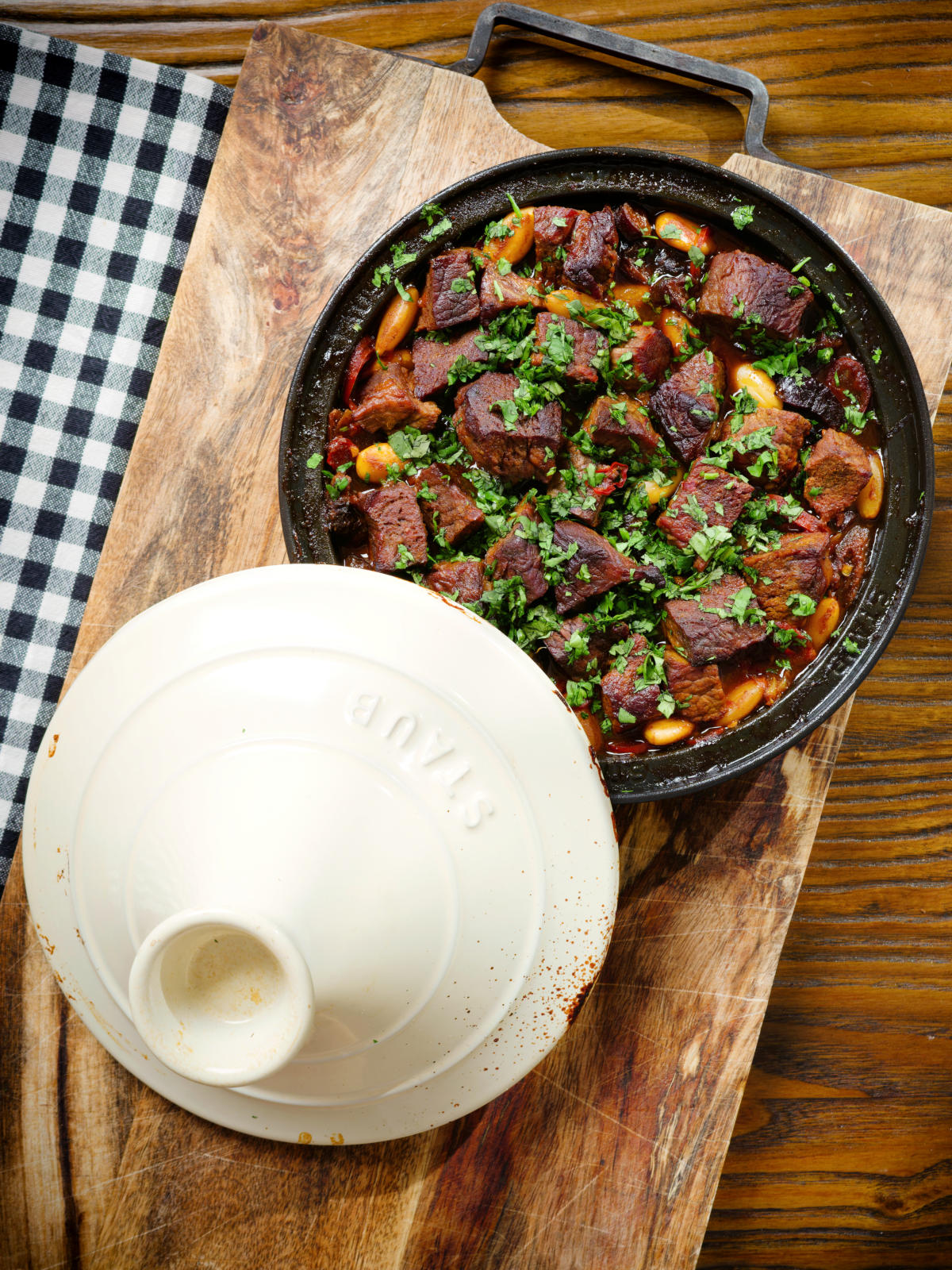 Overhead harissa beef tagine with prunes and almonds in a traditional style pot.