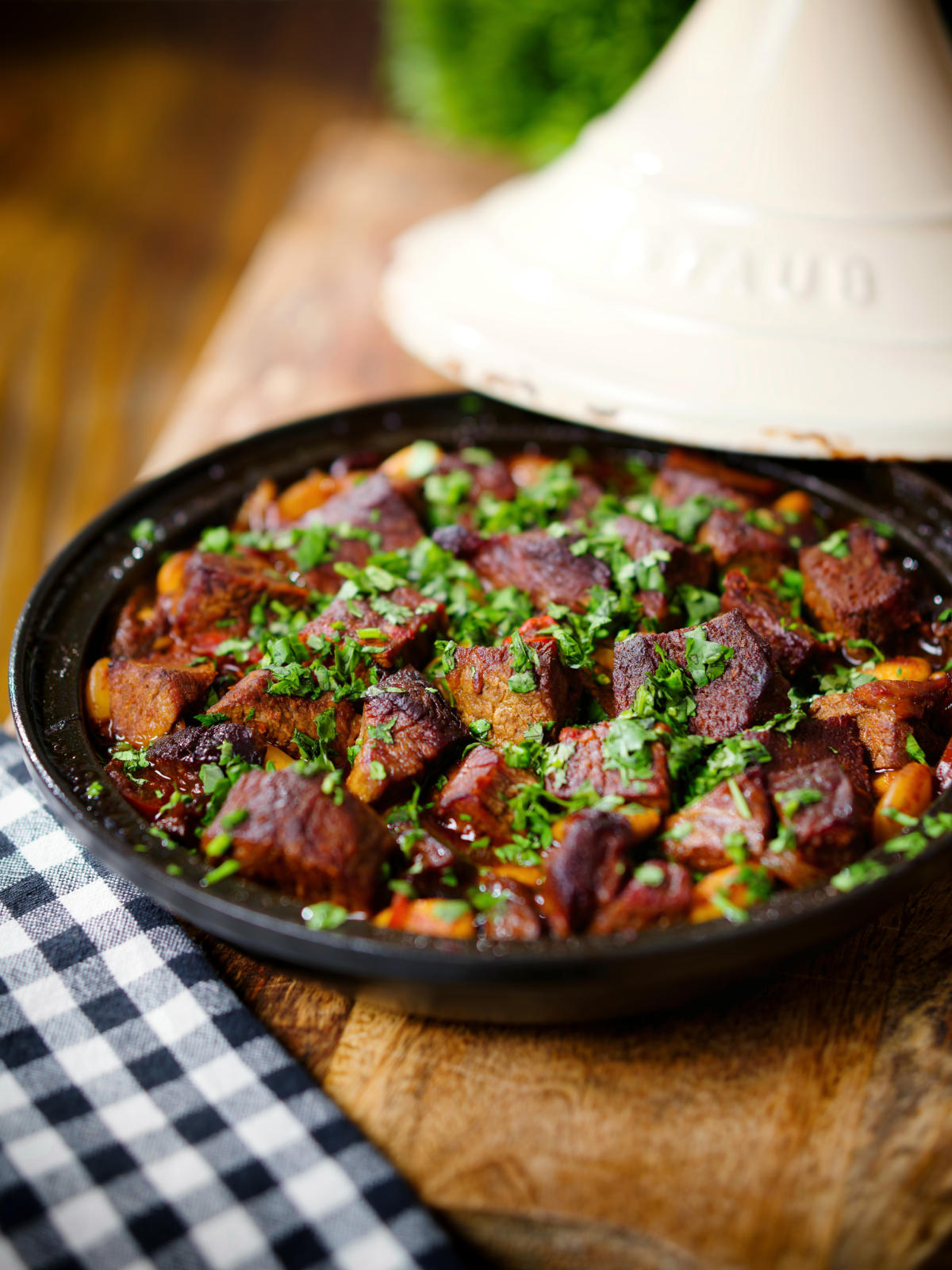 Overhead harissa beef tagine with prunes and almonds in a traditional style pot.