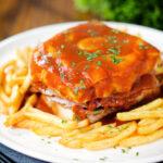 Portuguese francesinha sandwich served with a beer sauce and crispy French fries.