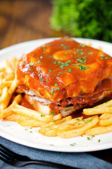 Portuguese francesinha sandwich served with a beer sauce and crispy French fries.