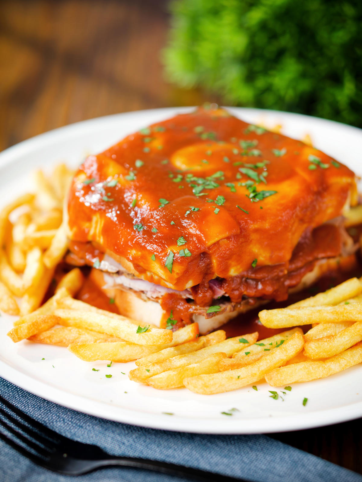 Portuguese francesinha sandwich served with a beer sauce and crispy French fries.