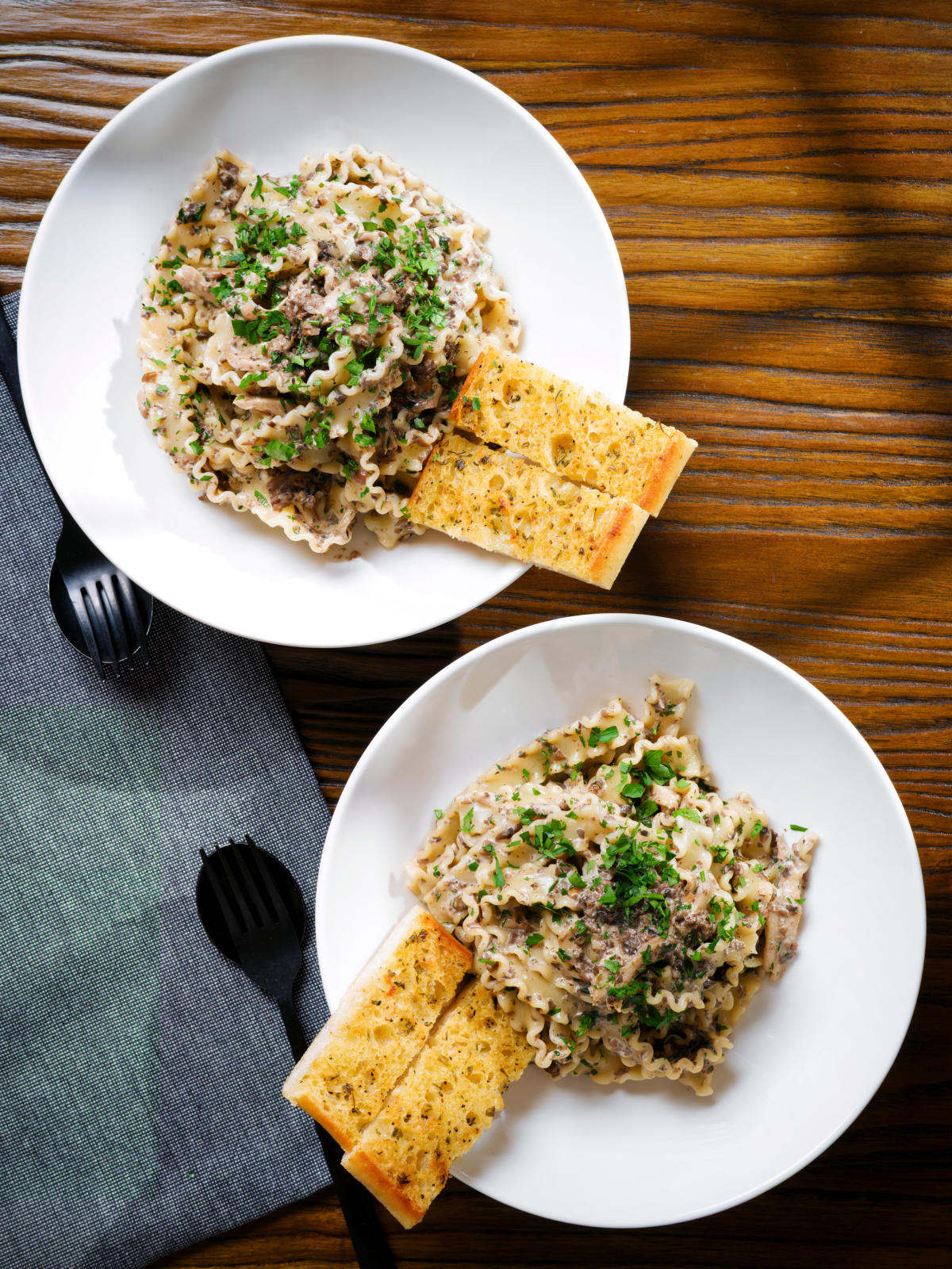 Overhead creamy garlic mushroom pasta served with fresh parsley and garlic bread.