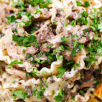 Close-up overhead creamy garlic mushroom pasta served with fresh parsley and garlic bread.