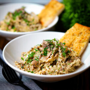 Creamy garlic mushroom pasta (mafaldine) with fresh parsley and garlic bread.