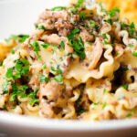 Close-up creamy garlic mushroom pasta served with fresh parsley and garlic bread.