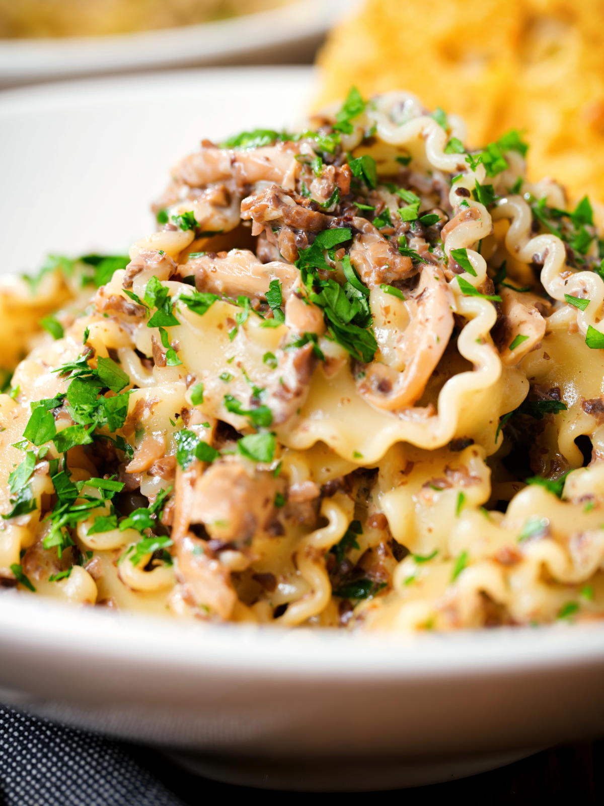 Close-up creamy garlic mushroom pasta served with fresh parsley and garlic bread.