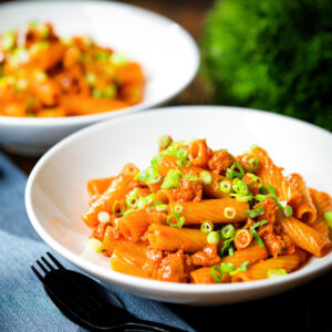 Spicy gochujang sausage pasta (rigatoni) garnished with spring onions.