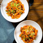 Overhead spicy gochujang sausage pasta garnished with spring onions.