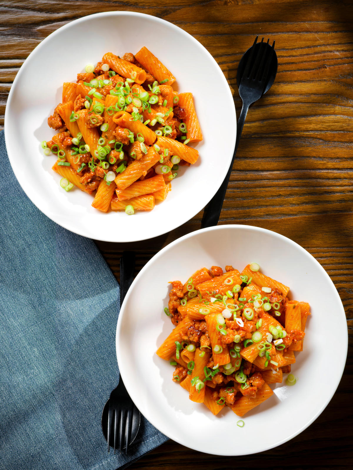 Overhead spicy gochujang sausage pasta garnished with spring onions.