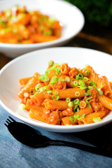 Spicy gochujang sausage pasta garnished with spring onions.