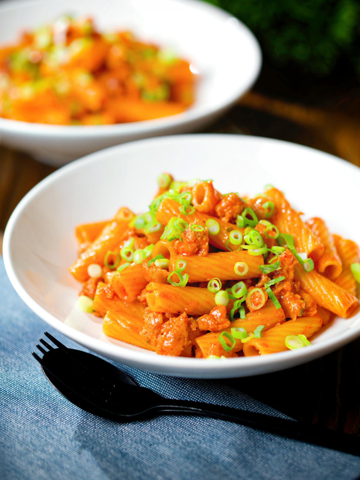 Spicy gochujang sausage pasta garnished with spring onions.