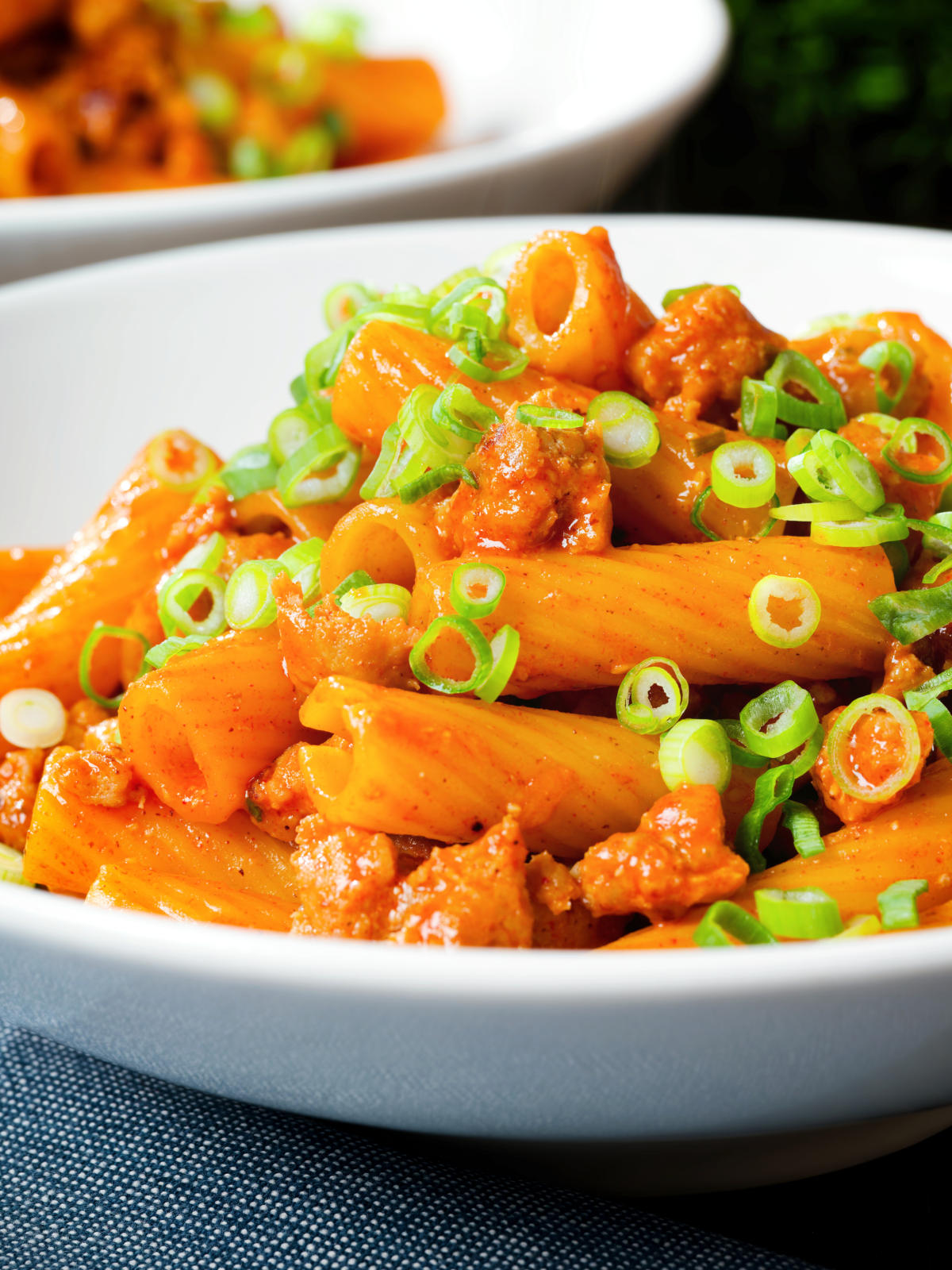 Close-up spicy gochujang sausage pasta garnished with spring onions.