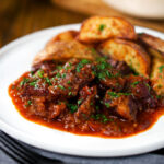 Greek beef kapama stew served with potato wedges.