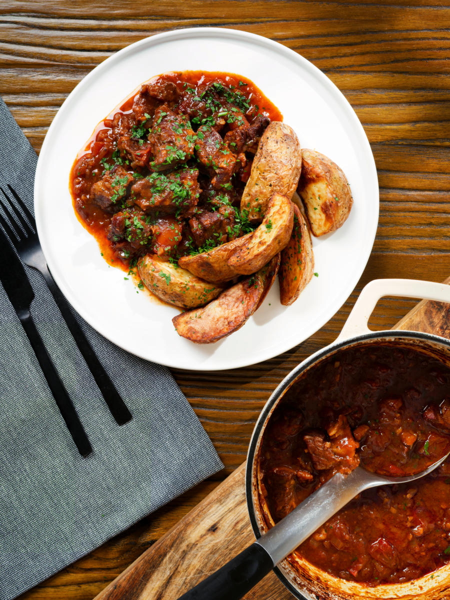 Overhead Greek beef kapama stew served with potato wedges.