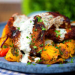 Close-up pan fried Indian masala lamb chops with Bombay potatoes and raita.