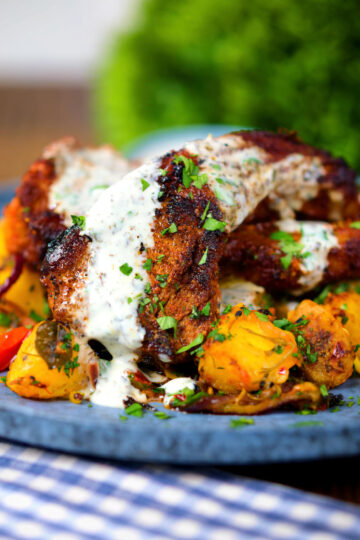 Close-up pan fried Indian masala lamb chops with Bombay potatoes and raita.