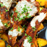Close-up overhead pan fried Indian masala lamb chops with Bombay potatoes and raita.