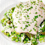 Close-up milk poached smoked haddock served with warm pea and feta salad.