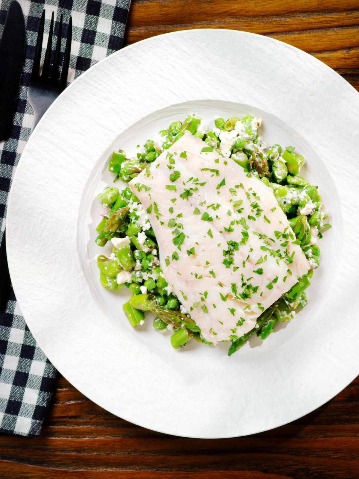 Overhead milk poached smoked haddock served with warm pea and feta salad.