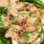 Close-up overhead pork tenderloin with prunes and brandy cream sauce, mashed potato and tenderstem broccoli.