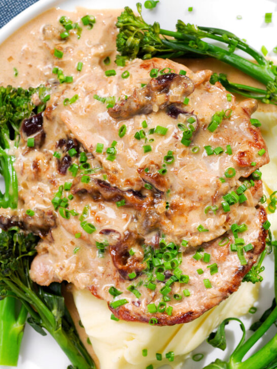 Close-up overhead pork tenderloin with prunes and brandy cream sauce, mashed potato and tenderstem broccoli.
